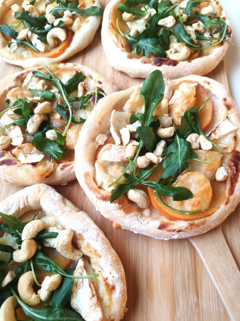 Pienet persimon-vuohenjuustopizzat rucolalla ja cashewpähkinöillä.