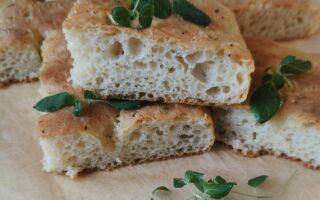 Yön yli kohotettu focaccia, jonka pinnalla oliiviöljyä, valkosipulia ja oreganoa