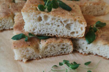 Yön yli kohotettu focaccia, jonka pinnalla oliiviöljyä, valkosipulia ja oreganoa